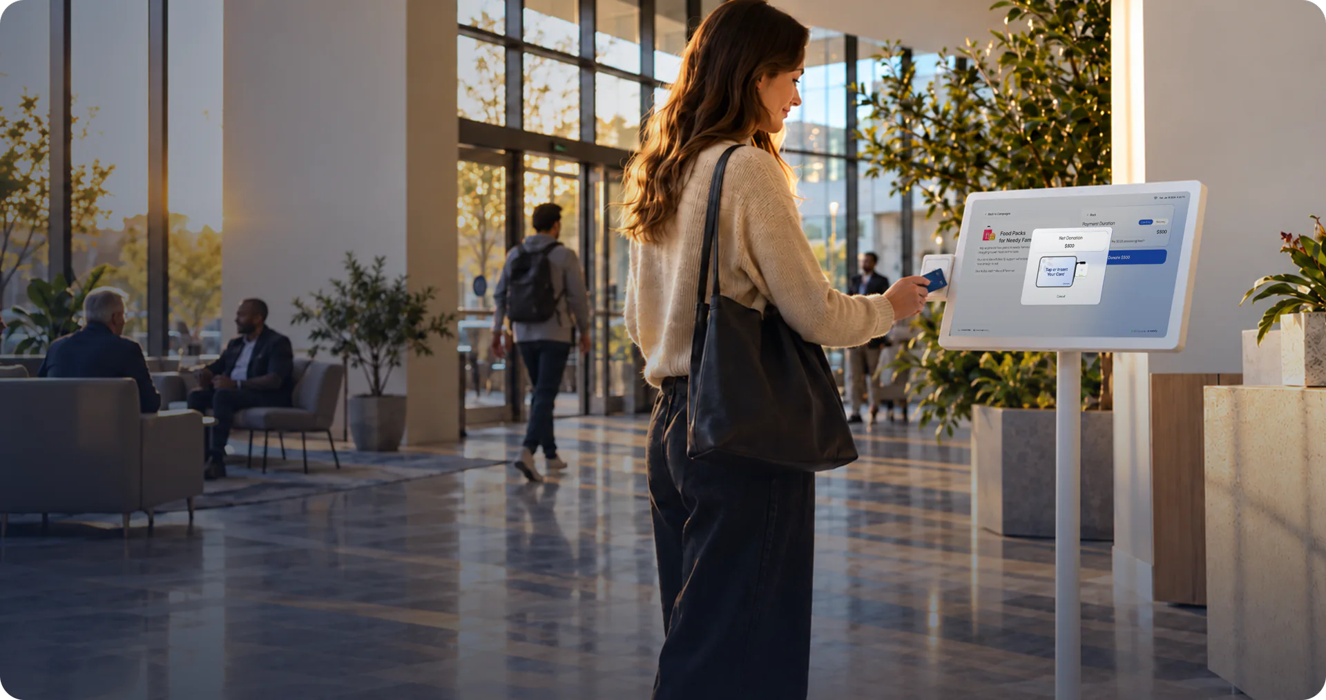 A donor taps a card on a floor-standing Donatefy kiosk in a sunlit community-center lobby